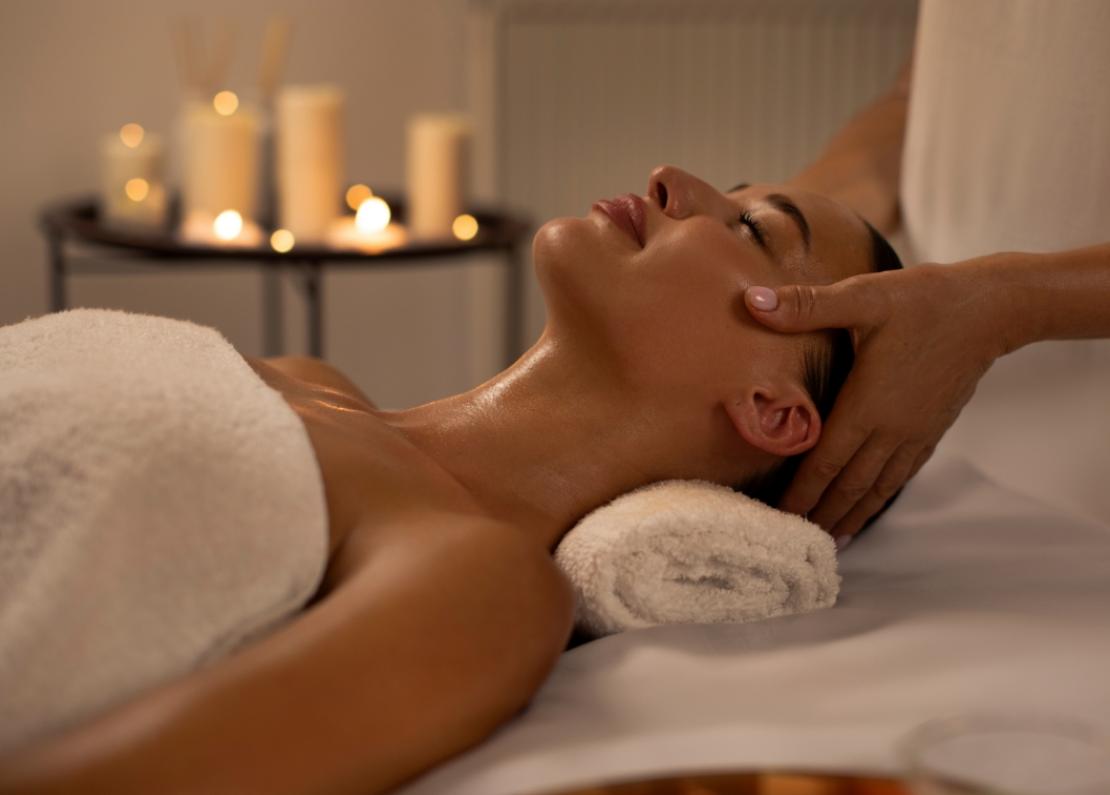 Massaggio rilassante in spa con candele accese sullo sfondo.