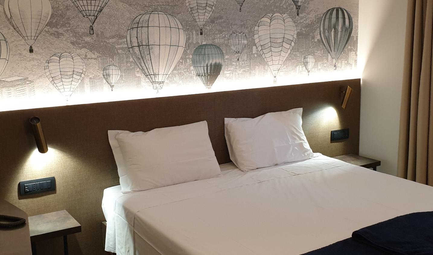 Camera da letto con testiera illuminata e sfondo di mongolfiere.