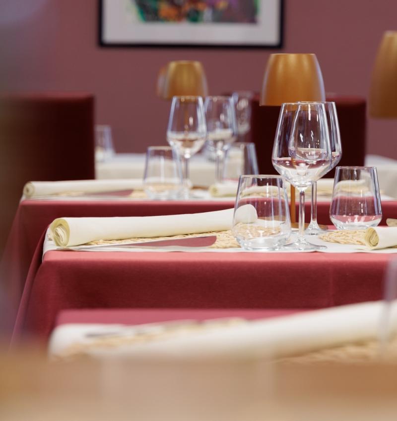 Tavoli apparecchiati con bicchieri e tovaglioli in un ristorante elegante.