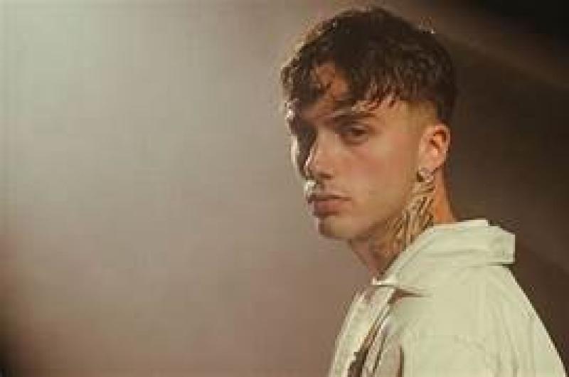 Giovane uomo con sguardo intenso e tatuaggi, atmosfera misteriosa.
