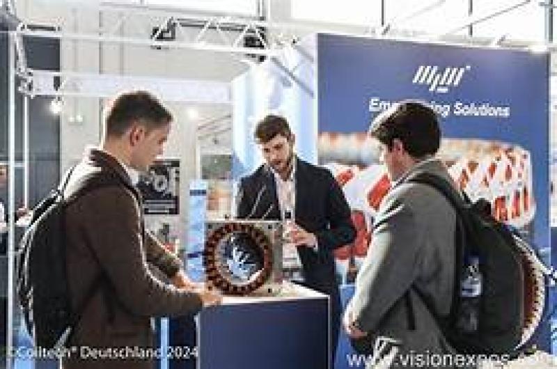 Tre uomini discutono un dispositivo tecnologico in una fiera luminosa.