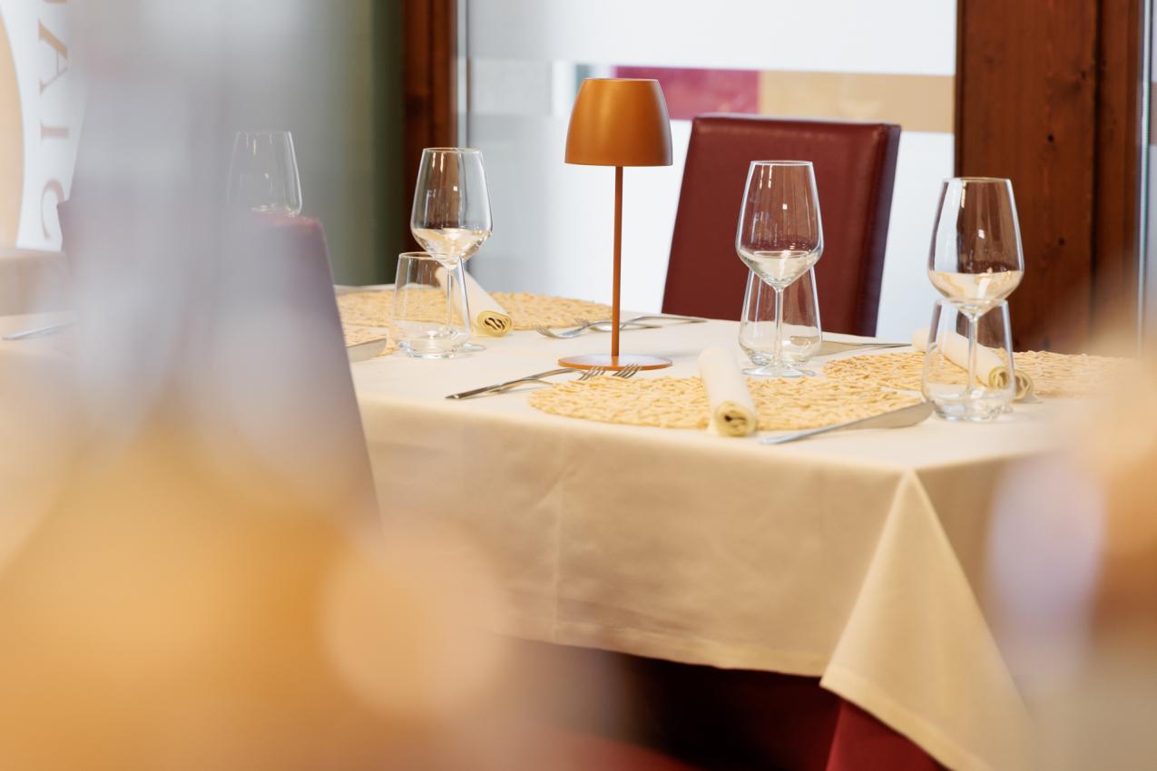 Tavolo elegante con bicchieri, tovaglioli arrotolati e lampada da tavolo moderna.
