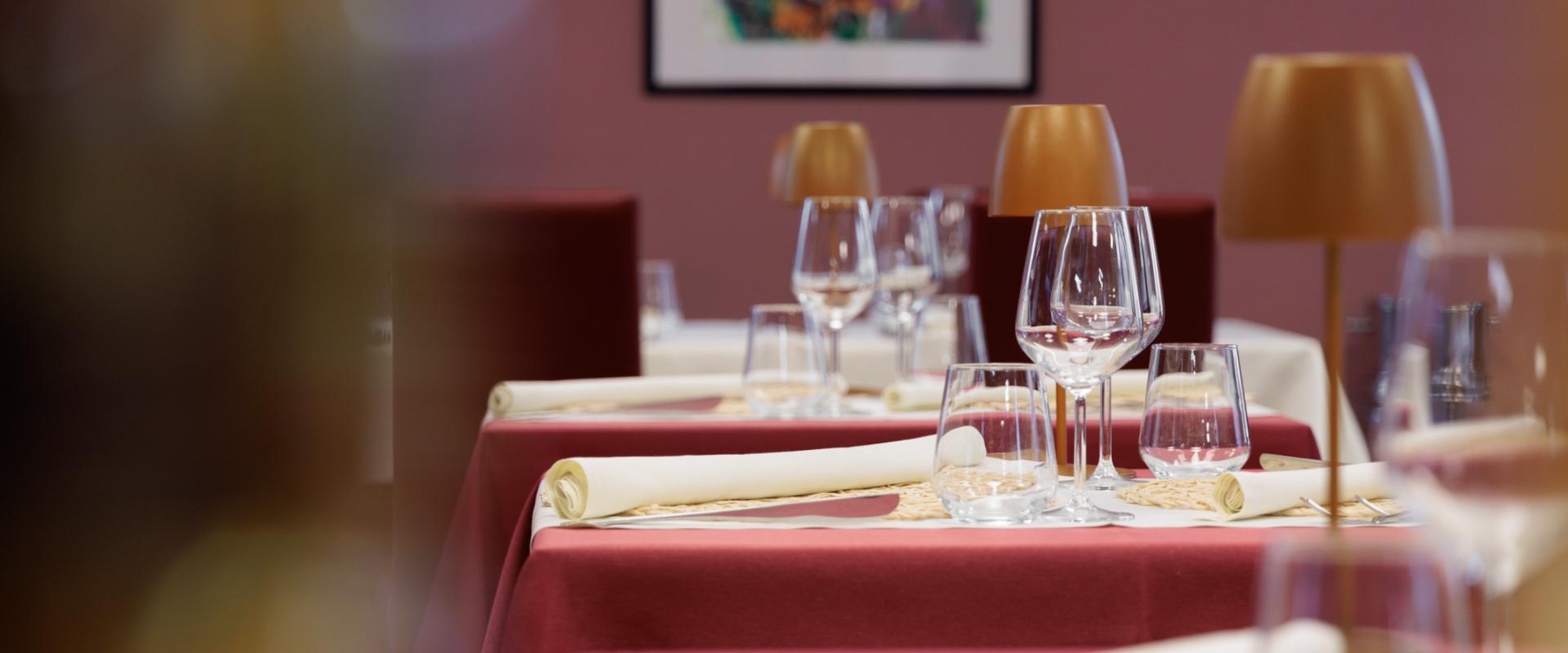 Tavoli apparecchiati con bicchieri e tovaglioli in un elegante ristorante.