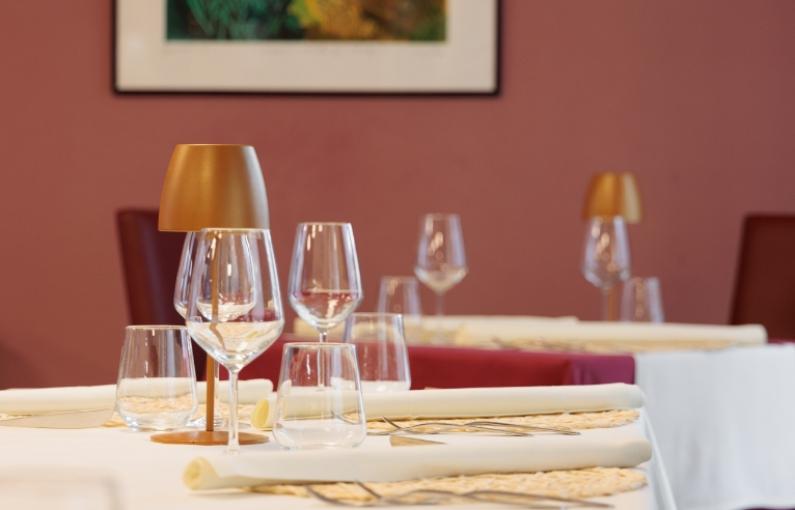 Tavoli eleganti con bicchieri e lampade in un ristorante raffinato.