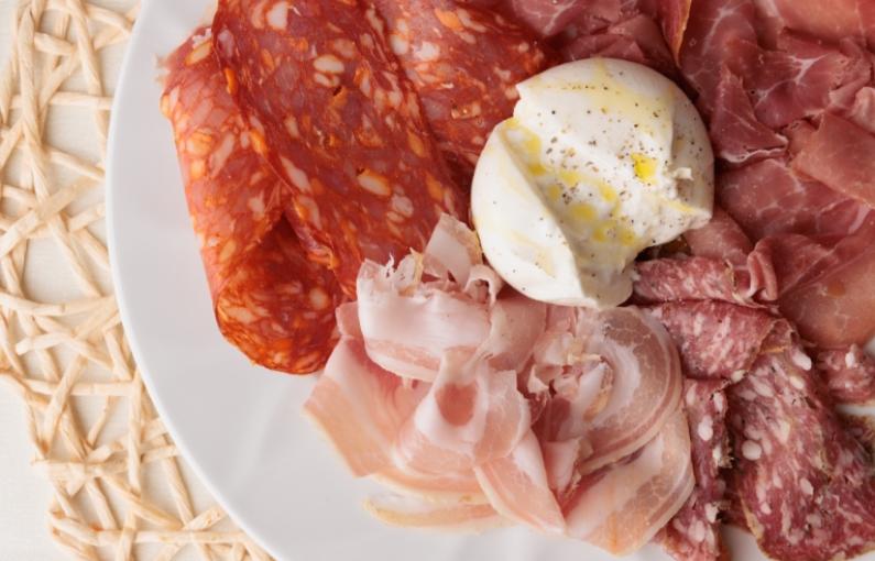 Tagliere di salumi assortiti con burrata su piatto bianco.